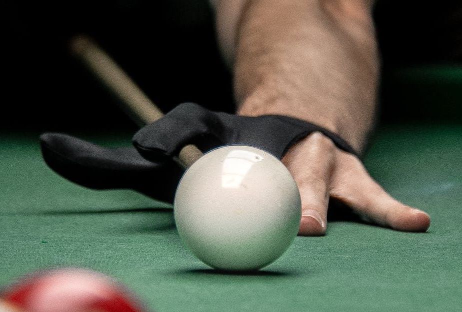 a person is playing pool with a cue and a ball .