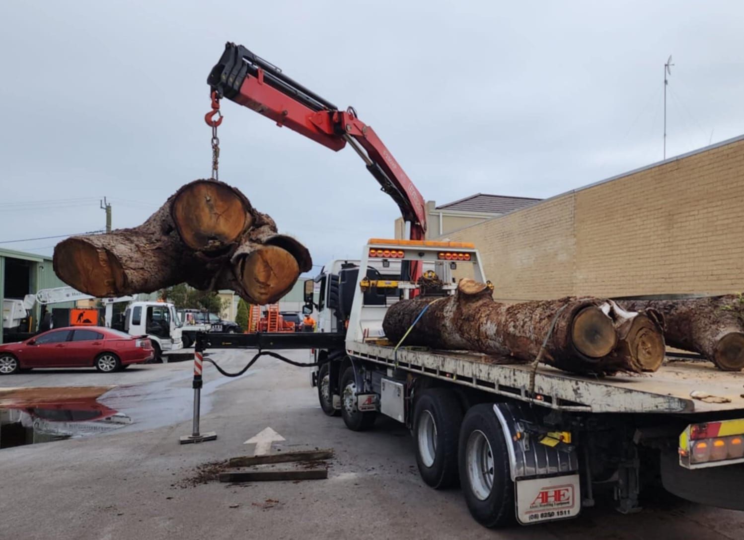 A truck with a crane attached to it is carrying logs.
