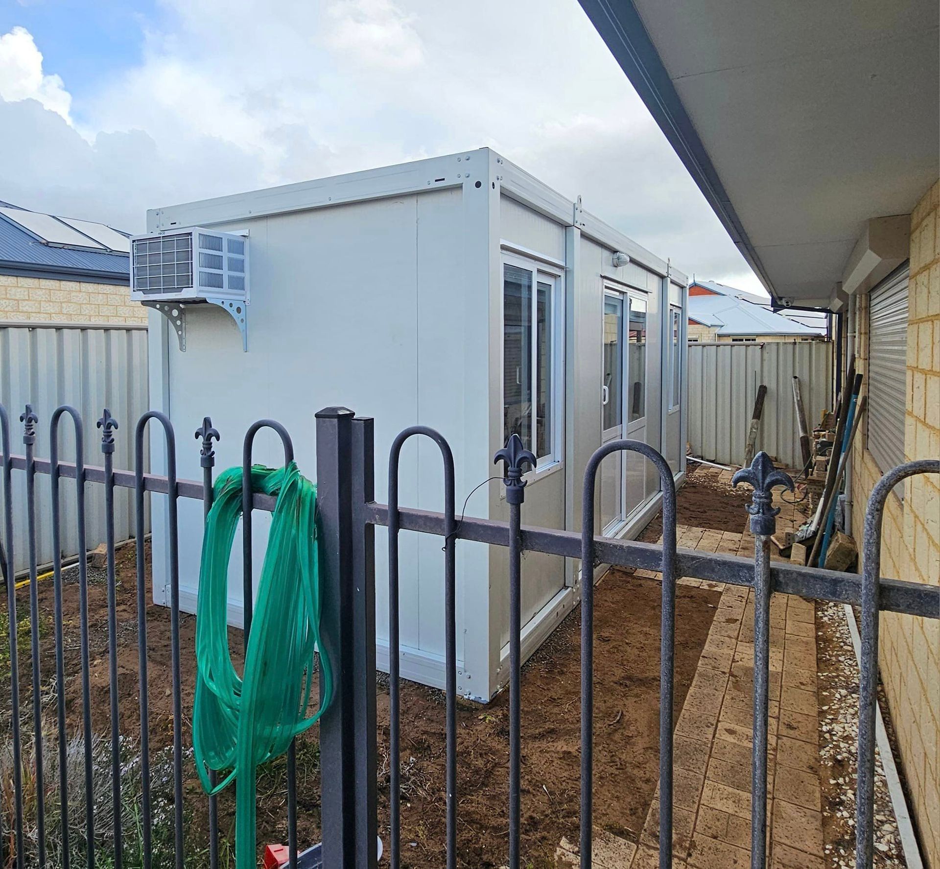 A large white building is behind a metal fence.