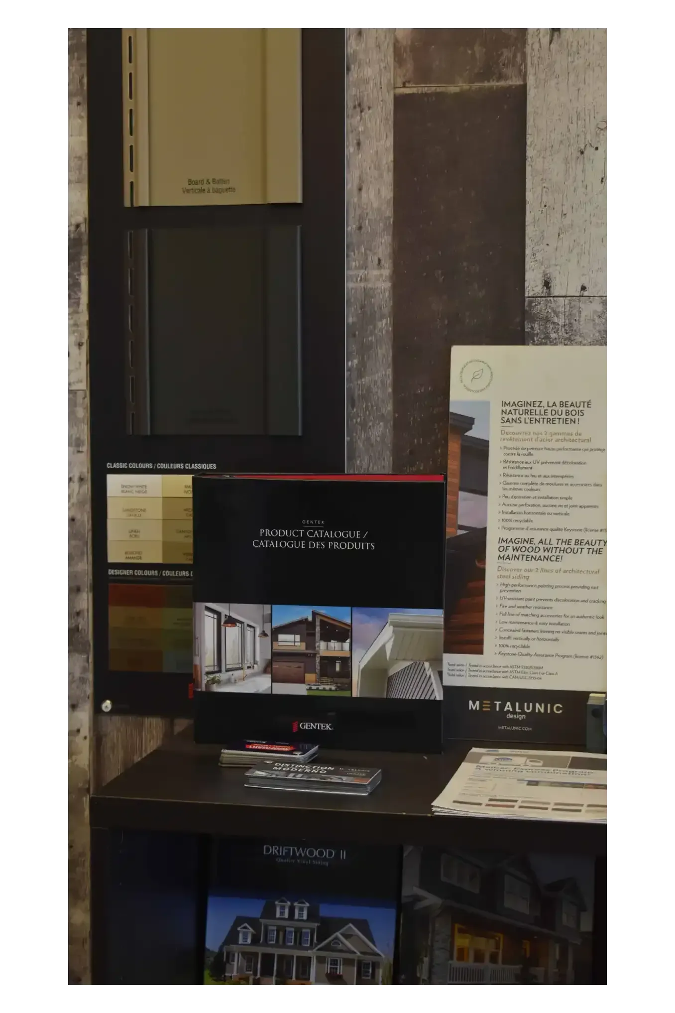 Display of paint samples, brochures, and color palettes on a dark wooden surface.
