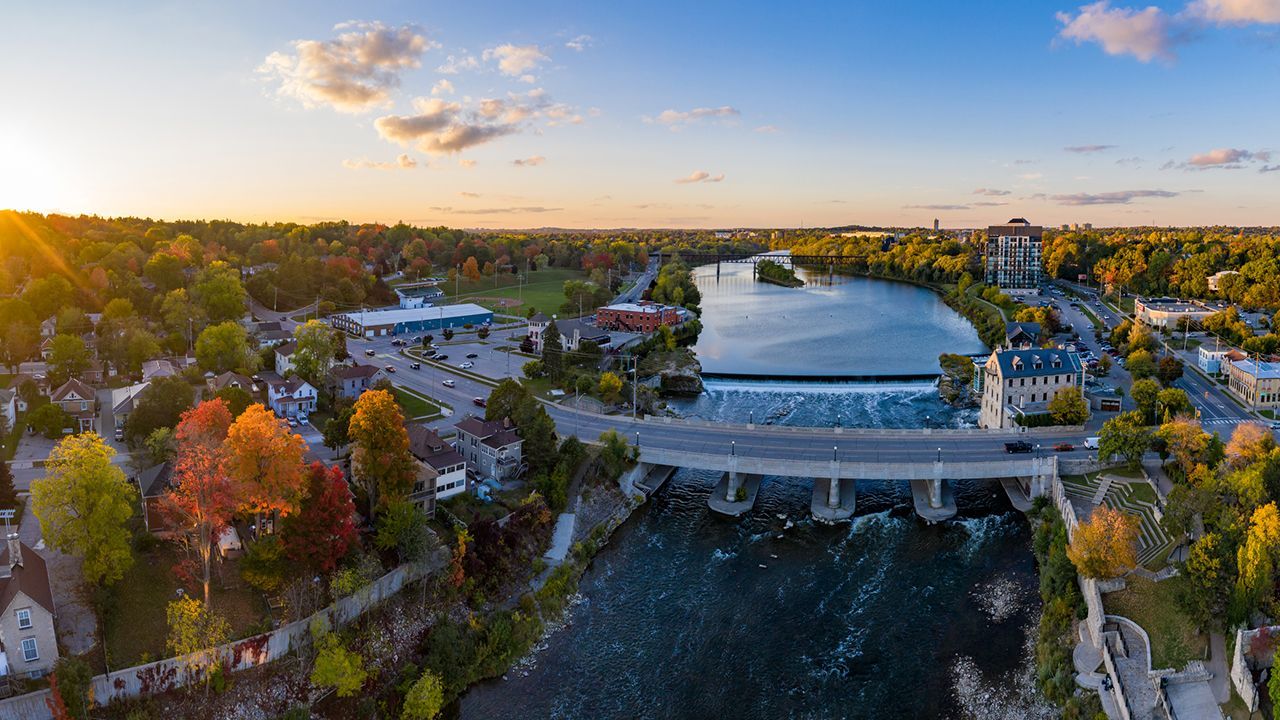 An aerial view of a city with a bridge over a river at sunset.