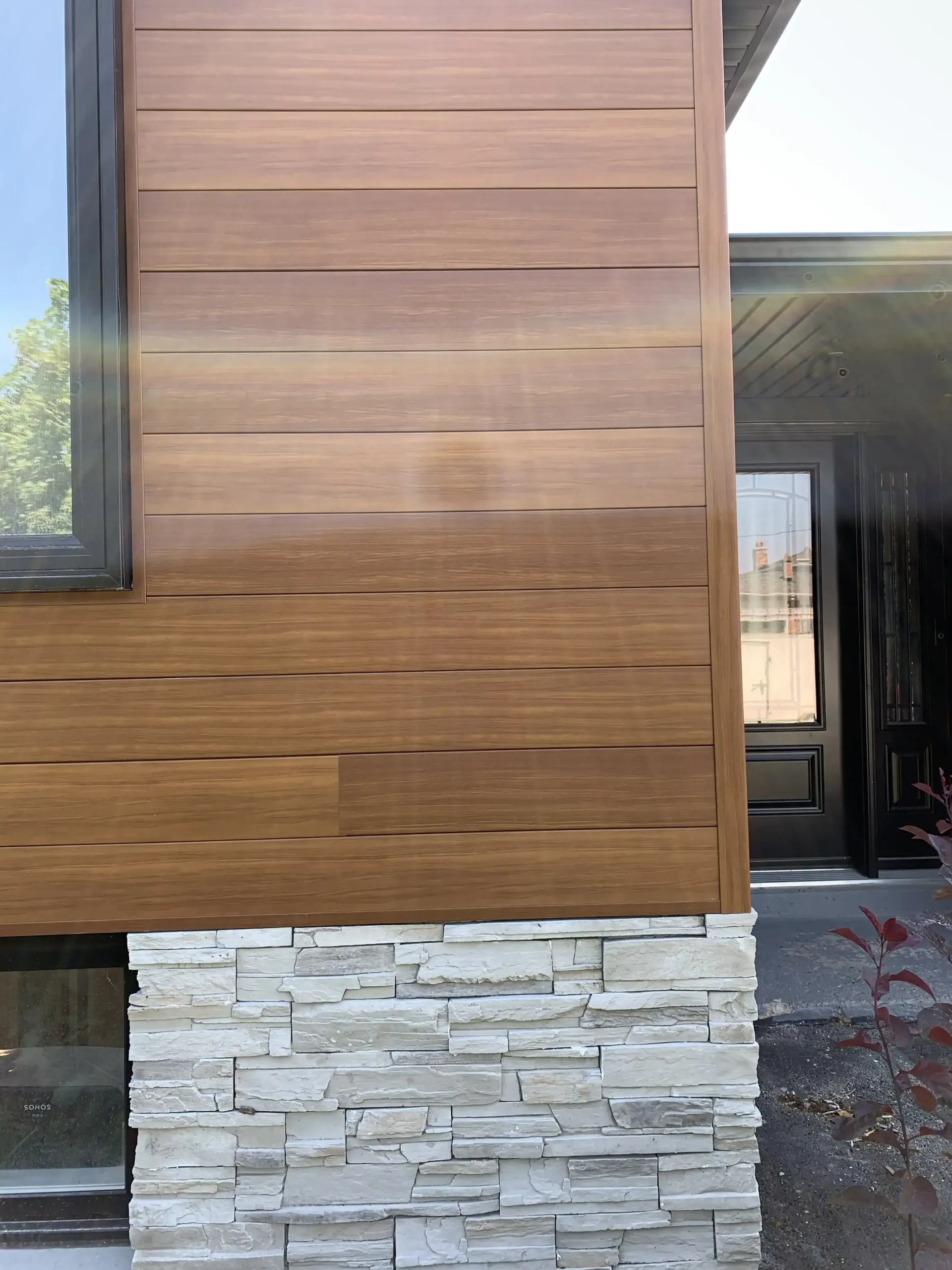 Black rain gutter on a house with light vertical siding and a dark roof.