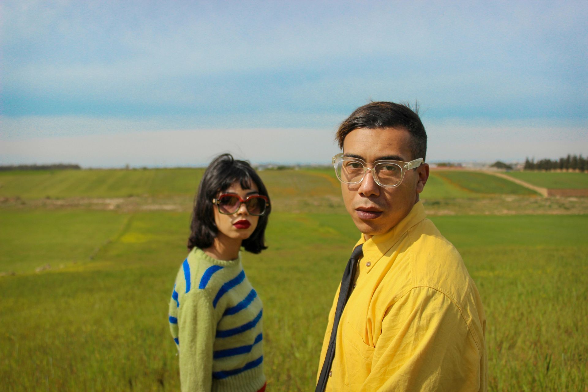 A man and a woman are standing in a grassy field.