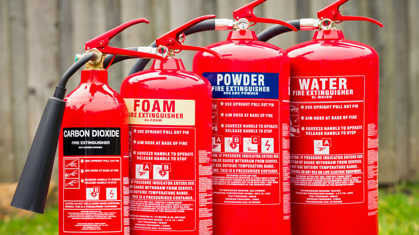 Four red fire extinguishers labeled carbon dioxide, foam, powder, and water.
