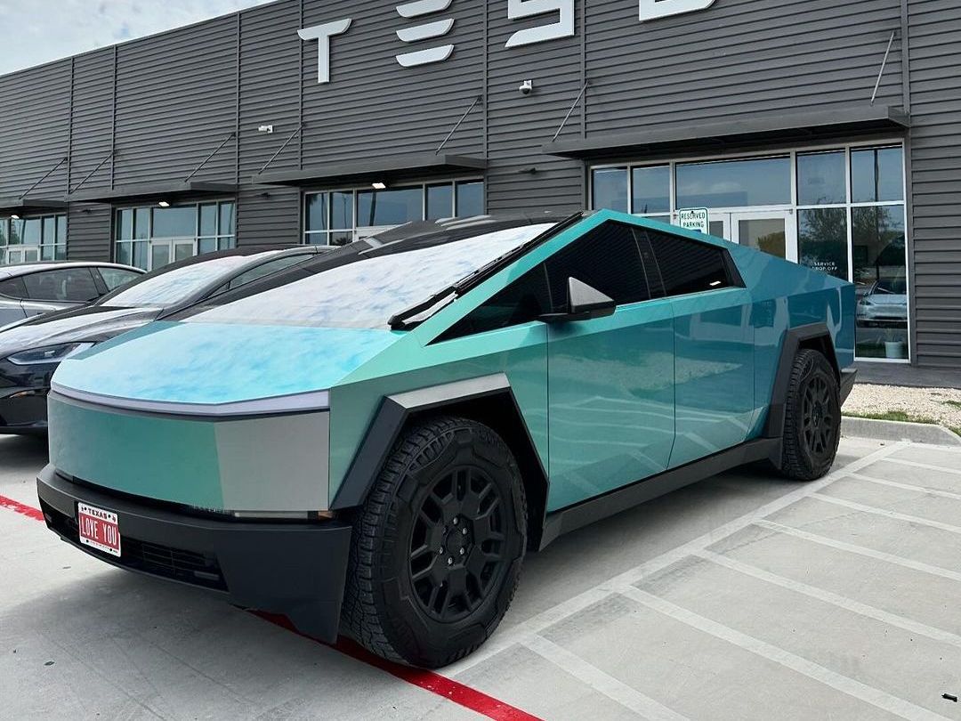 A tesla cybertruck is parked in front of a tesla store.