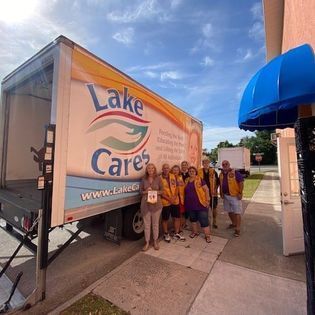 A group of people standing in front of a lake cares truck