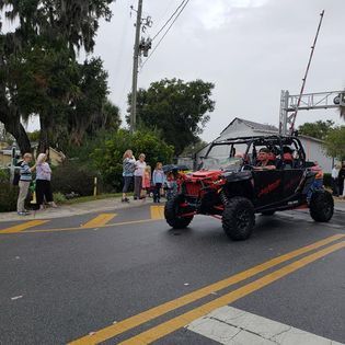 A man is driving a atv down a street in a parade.