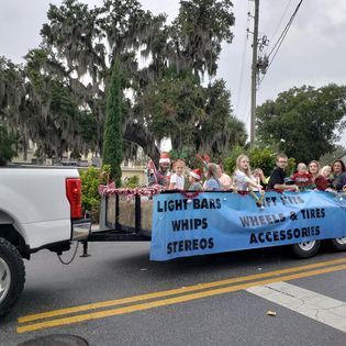 A group of people are riding on the back of a truck in a parade.