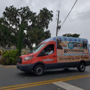 A red van with the word renningers on the side is driving down a street.