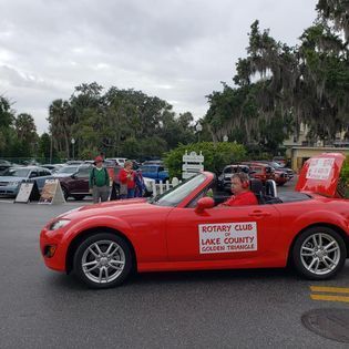 A red convertible car is parked in a parking lot.