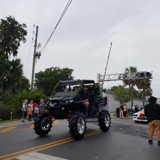 A man is driving an atv down a street in a parade.