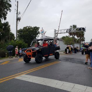 A group of people are riding an atv down a street in a parade.