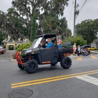 A man is riding a atv down a street in a parade.
