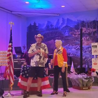 A man and a woman are standing in front of an american flag.