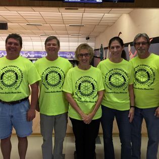 A group of people are posing for a picture in a bowling alley.