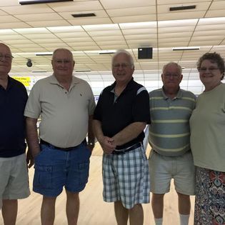 A group of men and women are posing for a picture in a bowling alley.