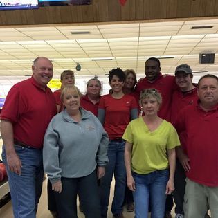 A group of people are posing for a picture in a bowling alley.