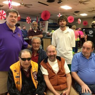 A group of men are posing for a picture in a bowling alley