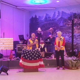 A man and a woman are standing in front of an american flag in a room.
