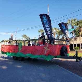 A group of people are riding on a red and green float in a parade.