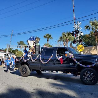 A black truck decorated for christmas is driving down a street.