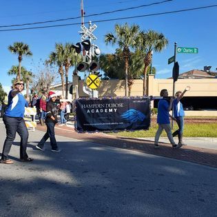 A group of people are walking down a street with a banner that says hampden durose academy.