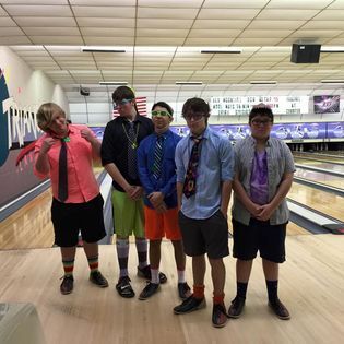 A group of young men are posing for a picture in a bowling alley.