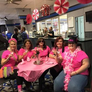 A group of women sitting around a table holding wine glasses