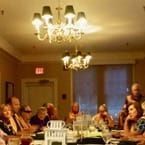 A group of people are sitting at tables in a room with a chandelier.