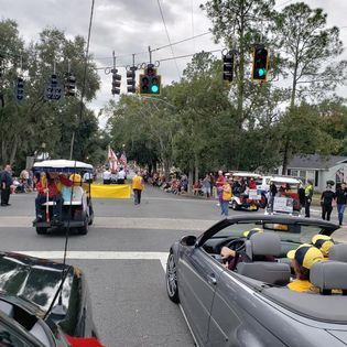 A convertible car is driving down a street in a parade.