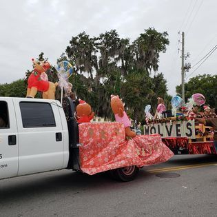 A white truck is pulling a float in a parade.