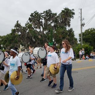 A group of people are marching down a street holding drums.
