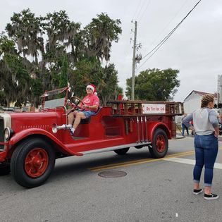 A woman is sitting on the back of an old red fire truck.
