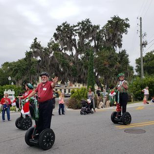 A group of people are riding segways down a street.