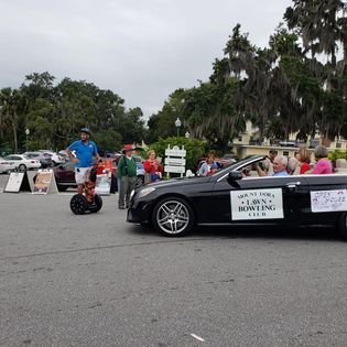 A group of people are standing around a black convertible car.