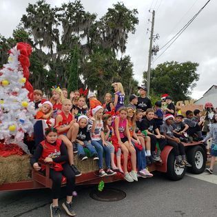 A group of children are sitting on the back of a float in a parade.