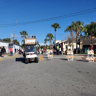 A golf cart is driving down a street in a parade.