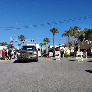 A truck with a wreath on it is driving down a street.