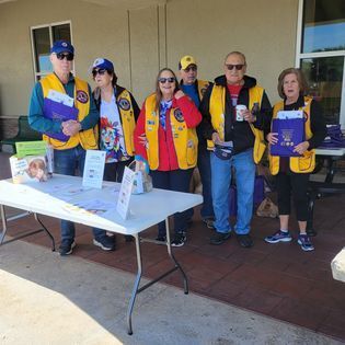 A group of people in yellow vests are standing around a table.