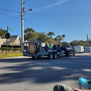 A person is sitting on the side of the road next to a float that says ' aa ' on it