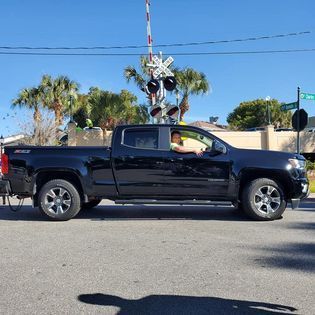 A black truck is parked in front of a railroad crossing