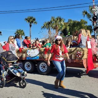 A woman in a santa hat is walking in front of a float in a parade.