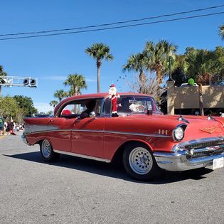 A red car with a santa claus on the windshield