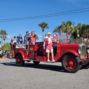 A group of people are riding on the back of a red fire truck.