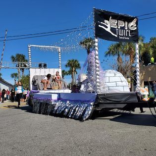 A parade with a float that says epic twirl on it