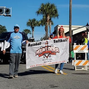A group of people are holding a banner that says baseball and softball.