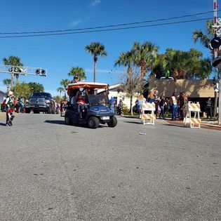 A group of people are riding in a golf cart down a street.