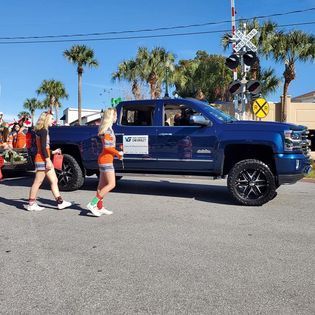A blue truck is parked on the side of the road next to a railroad crossing sign.