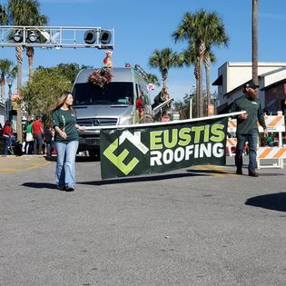 A group of people holding a eustis roofing banner