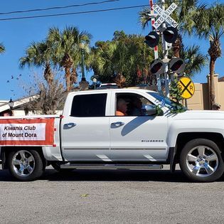 A white truck is parked in front of a railroad crossing sign